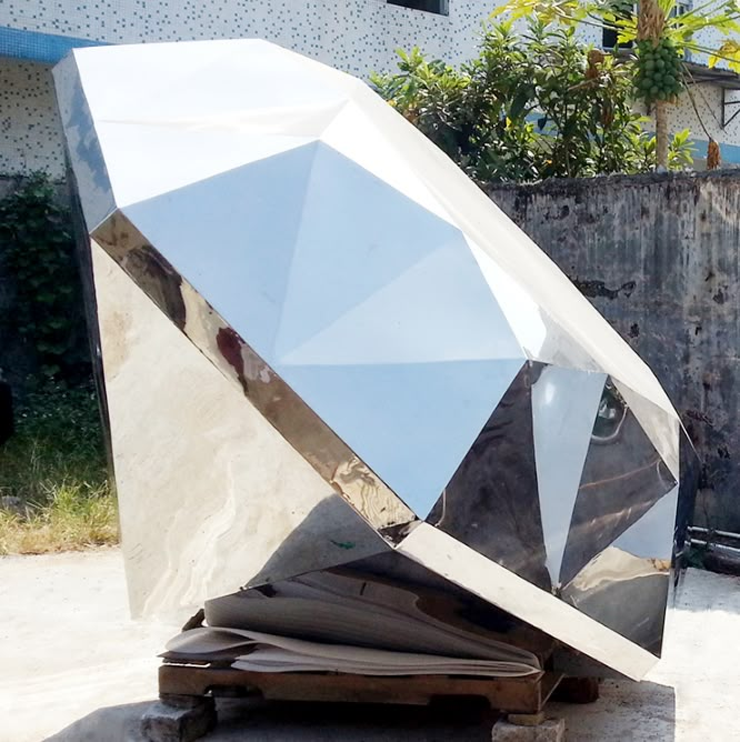 a large metal object sitting on top of a cement ground next to a fence and building