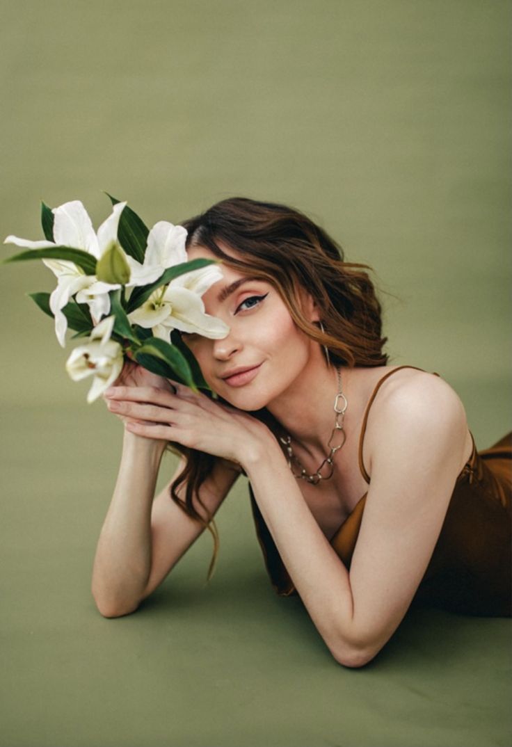 a woman laying on the ground with flowers in her hand