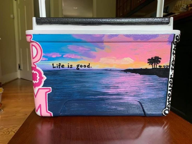 a cooler with the words life is good painted on it sitting on a wooden table