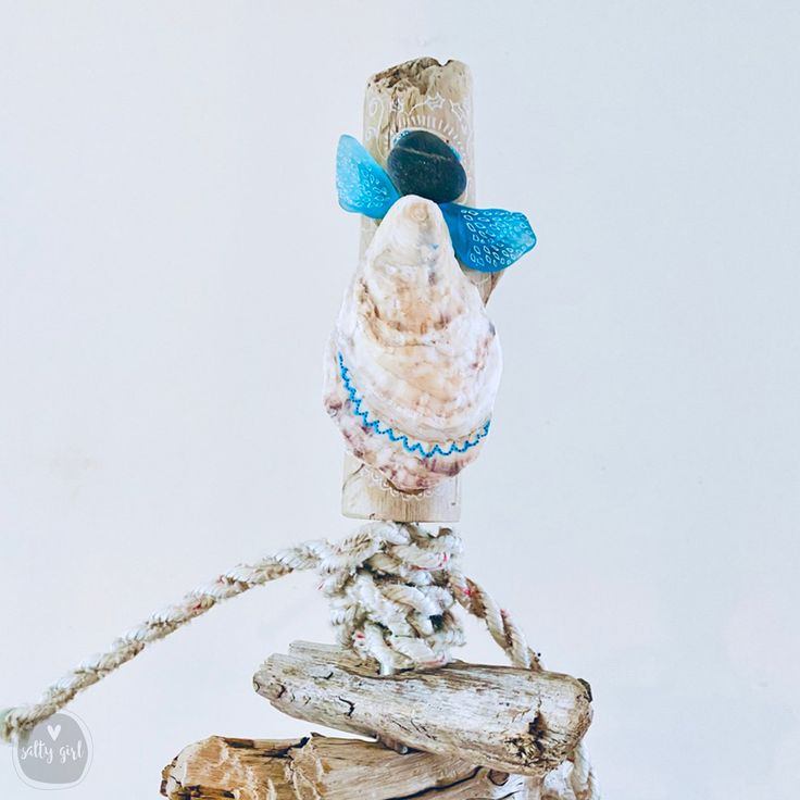 a bird is perched on top of a piece of driftwood with beads around its neck