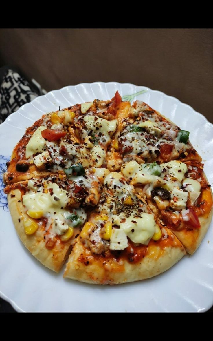 a pizza on a paper plate with cheese and toppings sitting on a table top