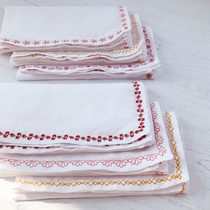 four white napkins with red and yellow designs are stacked on top of each other