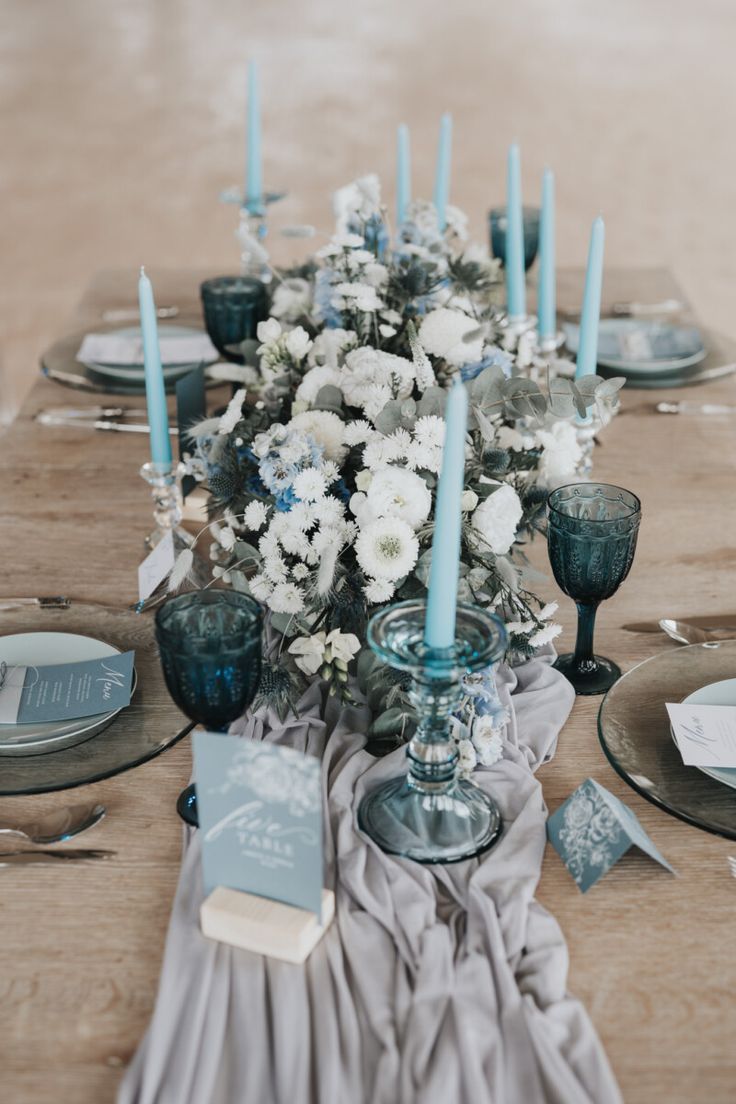 the table is set with blue candles and white flowers