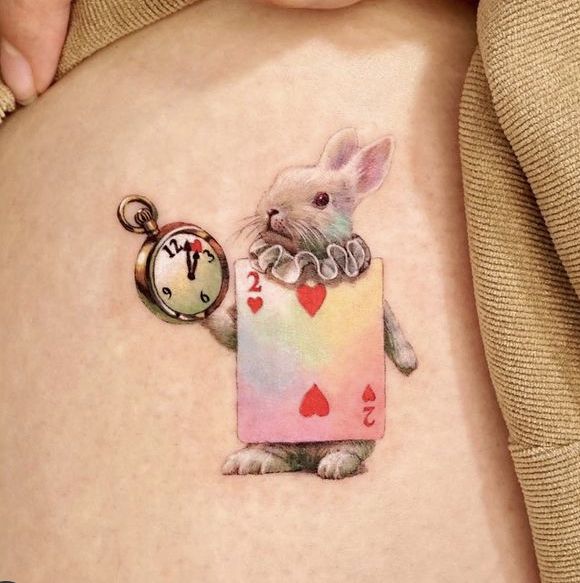 a woman's stomach with a rabbit tattoo on it and an alarm clock hanging from the side