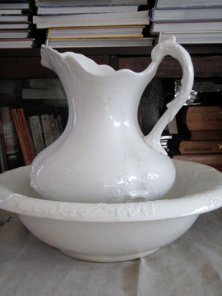 a white vase sitting in a bowl on top of a table