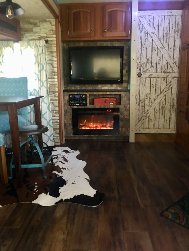 a living room with wood floors and a tv on the wall above an open fire place