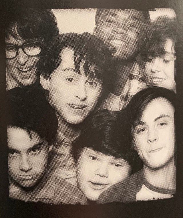 a group of young men posing for a photo in front of a black and white background