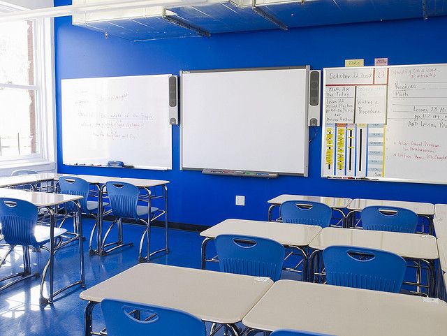 an empty classroom with blue chairs and whiteboards