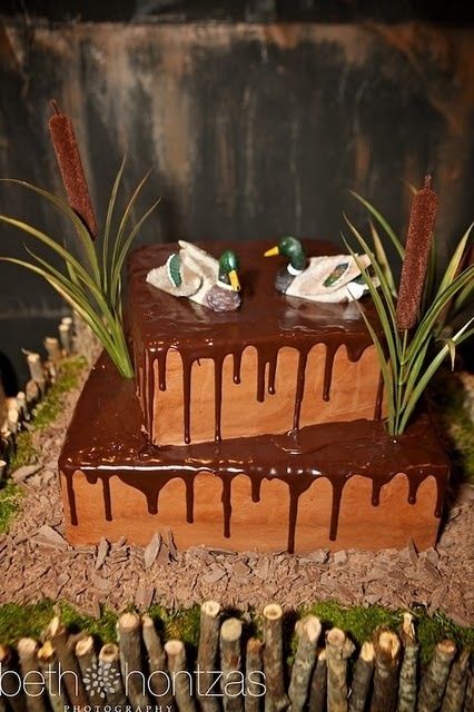 a cake with chocolate icing and ducks on top sitting in front of some grass