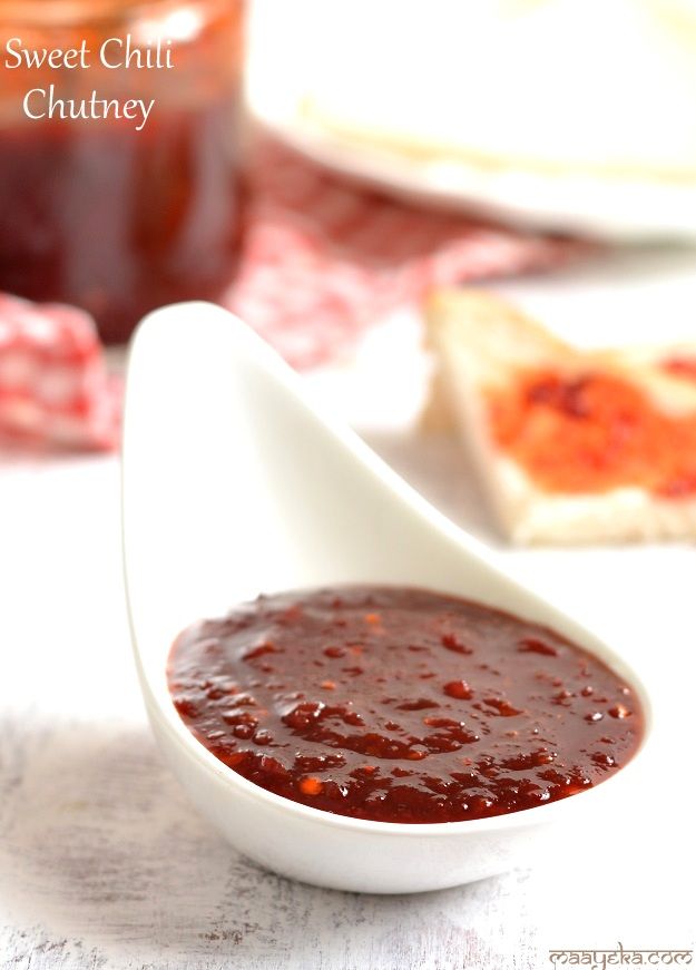 a spoon full of sauce sitting on top of a table next to some slices of bread