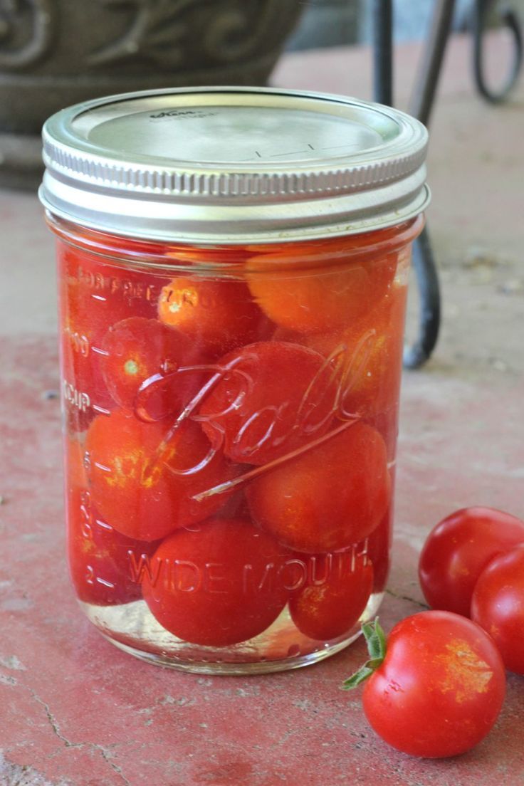 a jar filled with tomatoes sitting on top of a table