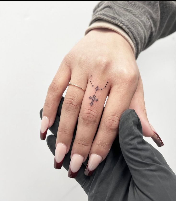 a woman's hand with a small cross tattoo on her left thumb and fingers