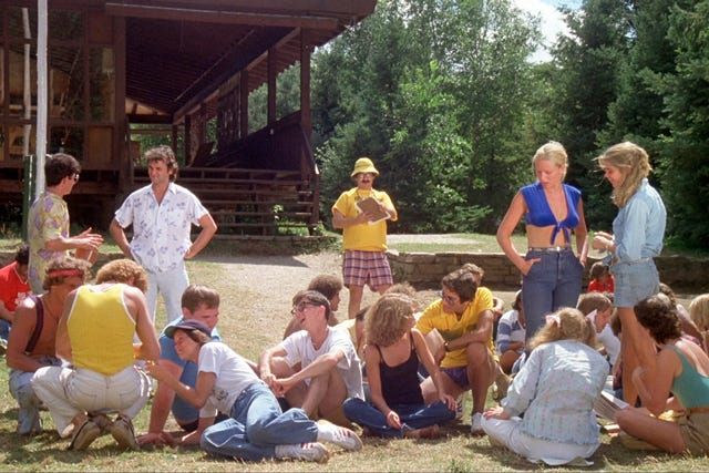 a group of people sitting and standing around each other in front of a wooden building