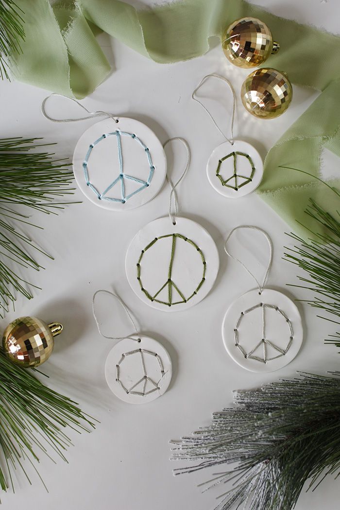 christmas ornaments with peace signs on them and pine branches in the foreground next to it