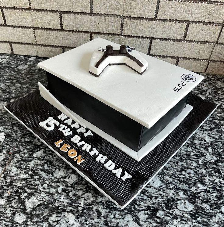 a birthday cake that is on top of a black and white box with the letter k