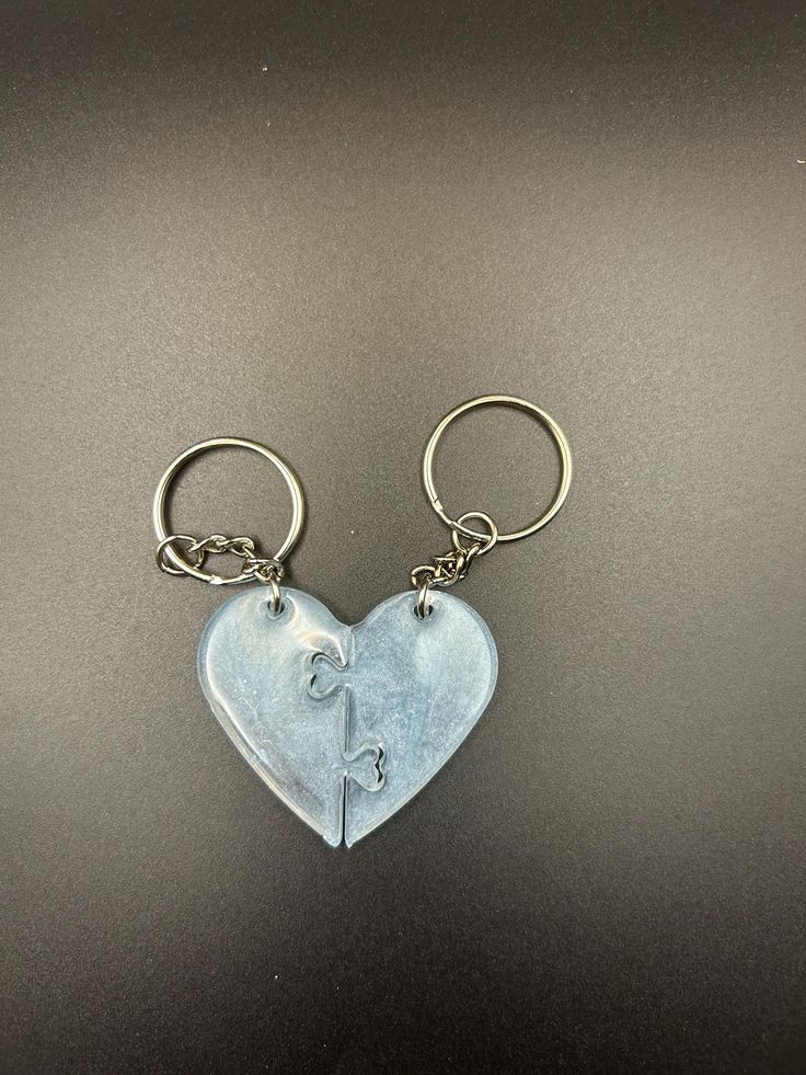 two heart shaped key chains on a black surface