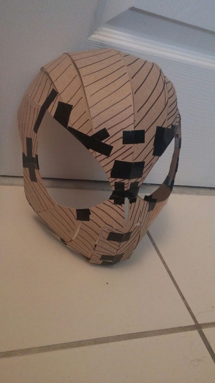 an origami mask sitting on the floor in front of a door with black tape