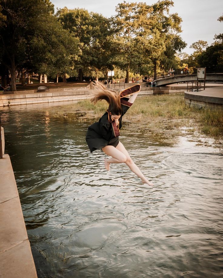 a woman jumping into the water with her hair in the air and wearing a tie