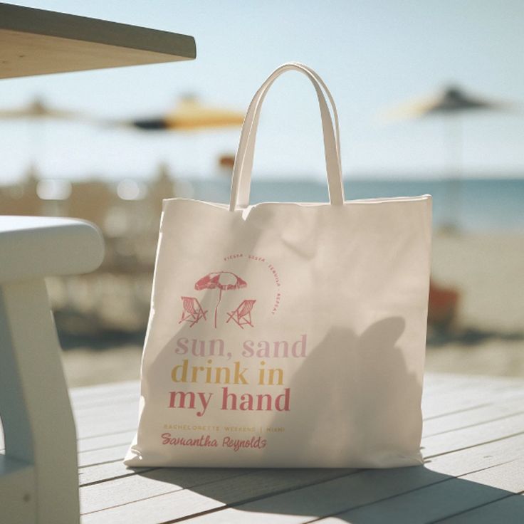 a white bag sitting on top of a wooden table next to an umbrella covered beach