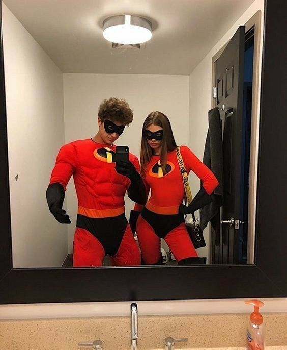 a man and woman dressed as the incredibles in front of a mirror