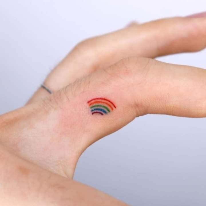 a person's hand with a small rainbow tattoo on it