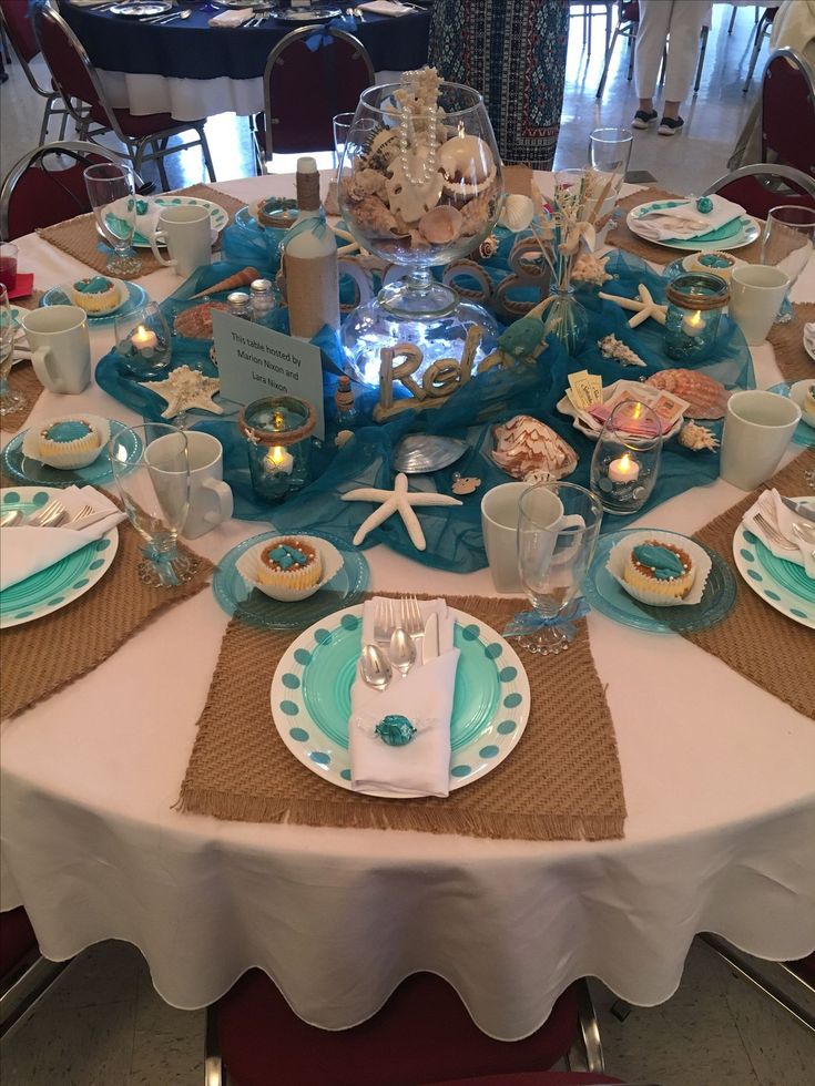 the table is set with plates, cups and saucers for an ocean themed celebration