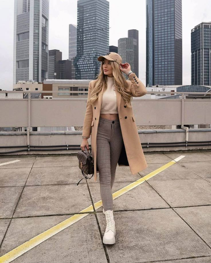 a woman walking across an airport tarmac wearing a tan coat and matching pants with white tennis shoes