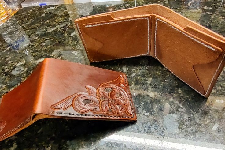 two leather wallets sitting on top of a counter