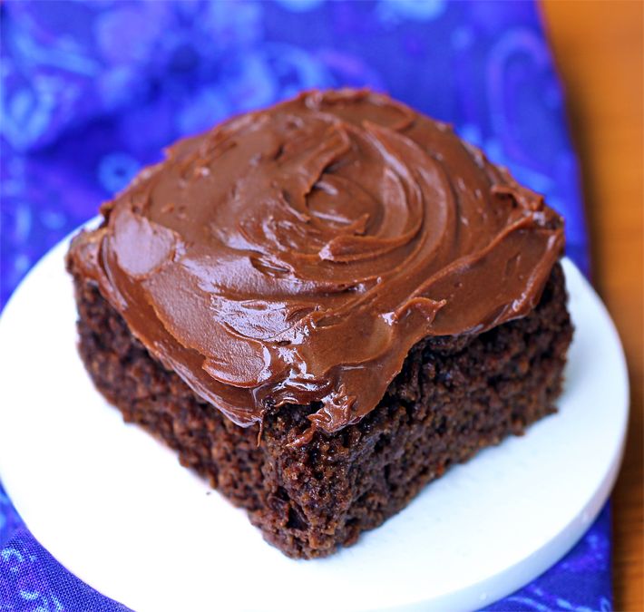 a piece of chocolate cake sitting on top of a white plate next to a blue napkin