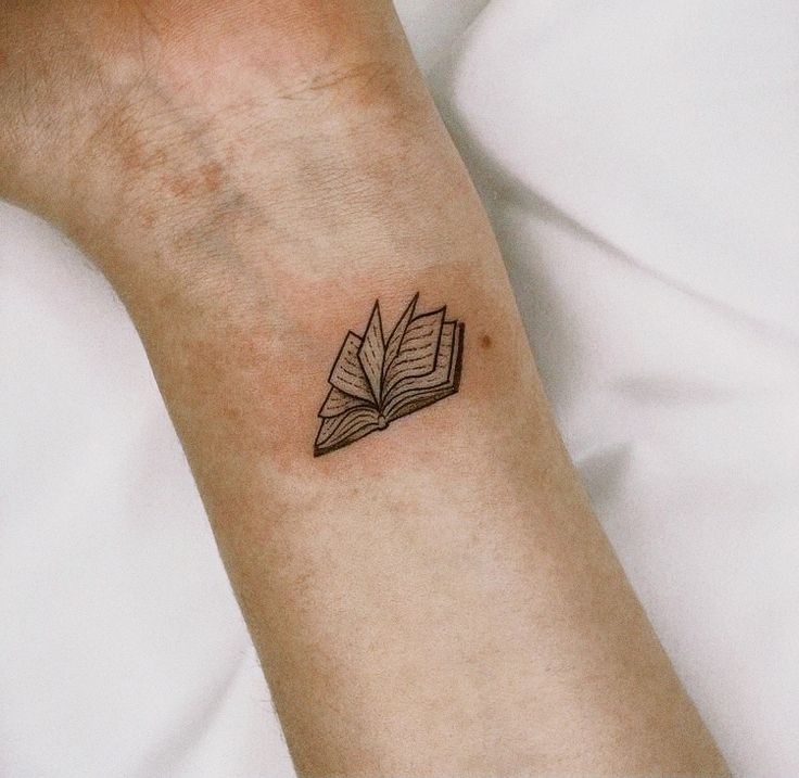 a person with a book tattoo on their arm