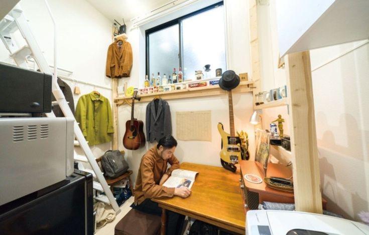 a person sitting at a table with a book in front of him and guitar hanging on the wall