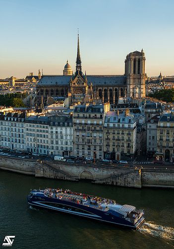 a large boat traveling down a river next to tall buildings and a cathedral in the background