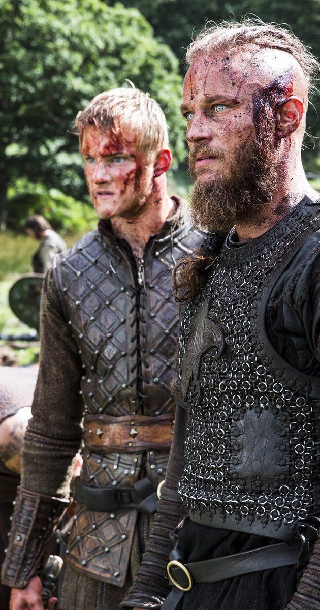 two men with blood on their faces standing next to each other in front of trees