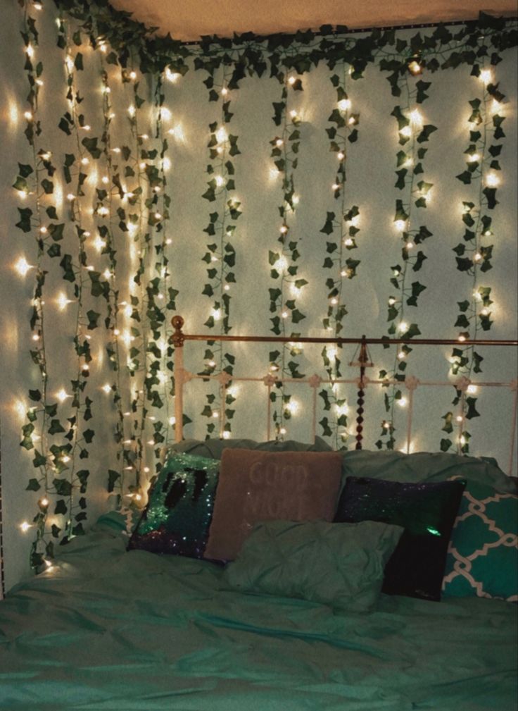 a bed that has some lights on the headboard and pillows in front of it