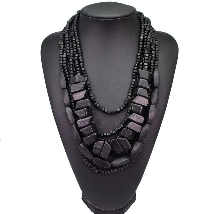 Discover the epitome of earthy elegance with our Bohemian Black Beaded Necklace, meticulously handcrafted to grace your ensemble with a touch of African tribal inspiration. This multi-strand statement piece boasts a harmonious blend of polished wooden elements and lustrous black beads, cascading in layers to create a bold aesthetic that's both timeless and contemporary. Perfectly suited for the fashion-forward individual, this necklace promises to be a versatile addition to your jewelry collecti Bohemian Multi-strand Black Bead Jewelry, Elegant Multi-strand Necklaces With Wooden Beads, Elegant Multi-strand Necklace With Wooden Beads, Black Bohemian Jewelry With Polished Beads, Bohemian Black Multi-strand Beads, Black Bohemian Multi-strand Beads, Bohemian Black Beaded Necklaces, Elegant Multi-strand Wooden Beads, Bohemian Beaded Necklaces With Round Beads