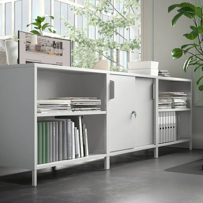 a white bookcase sitting next to a potted plant