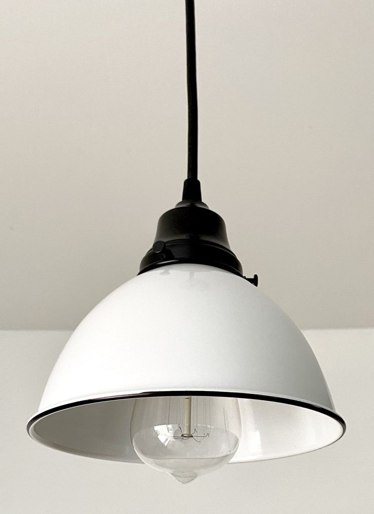 a white light hanging from a ceiling with a black cord attached to the end of it