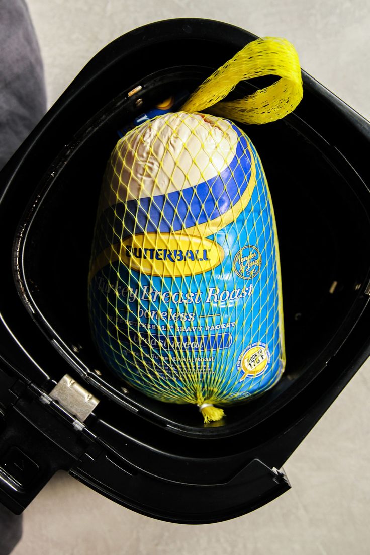 a bag is sitting in an open trash can with a yellow string on it's handle