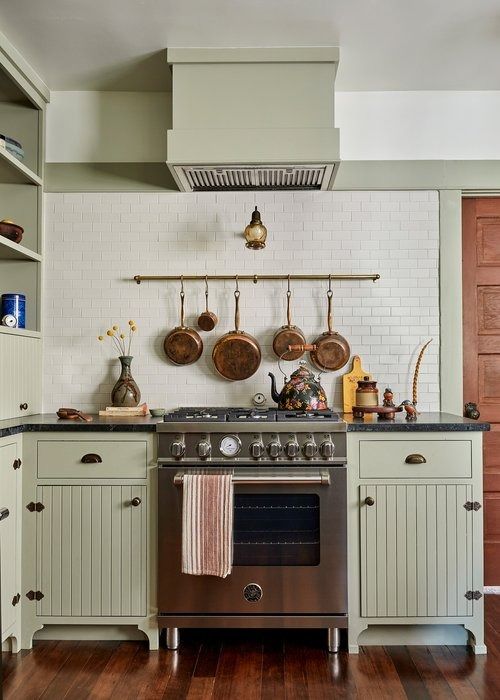 a stove top oven sitting inside of a kitchen next to wooden flooring and cabinets