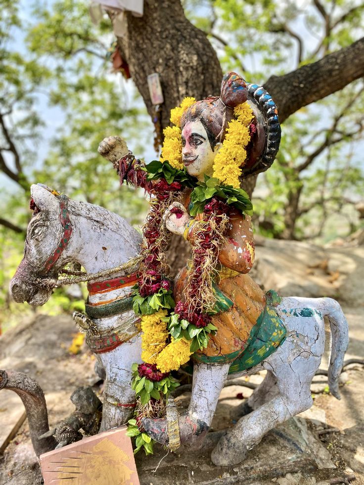 a statue of a man riding on top of a white horse next to a tree