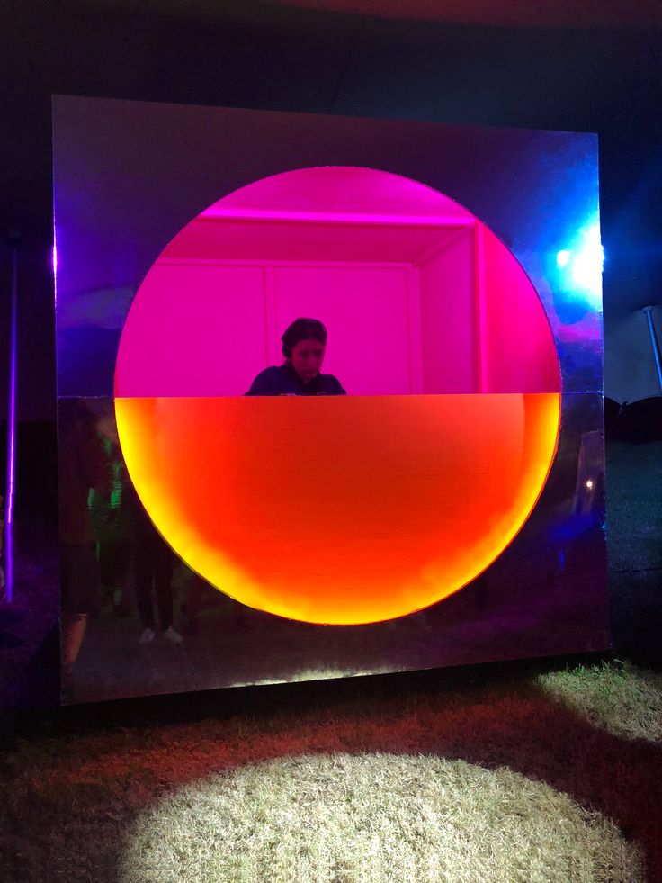 a man standing in front of a mirror with an orange and pink ball on it