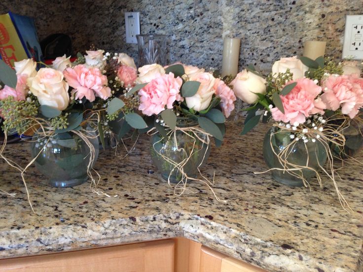 four vases filled with pink and white flowers sitting on top of a kitchen counter