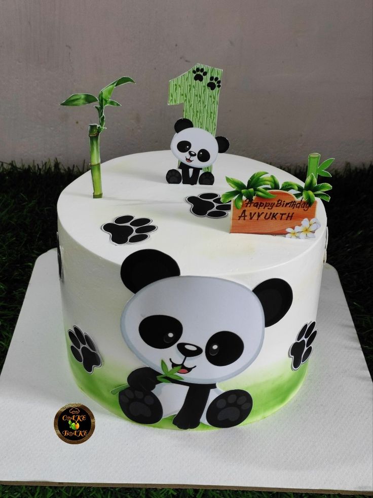 a panda bear themed cake is sitting on a table with green grass and bamboo trees