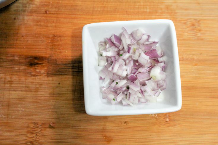 chopped onions in a white bowl on a wooden table