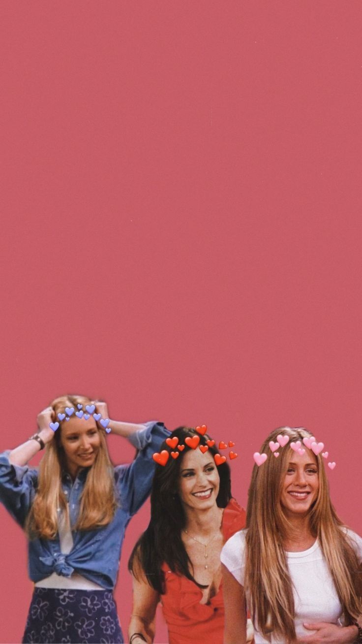 three women standing next to each other in front of a pink wall with flowers on their head