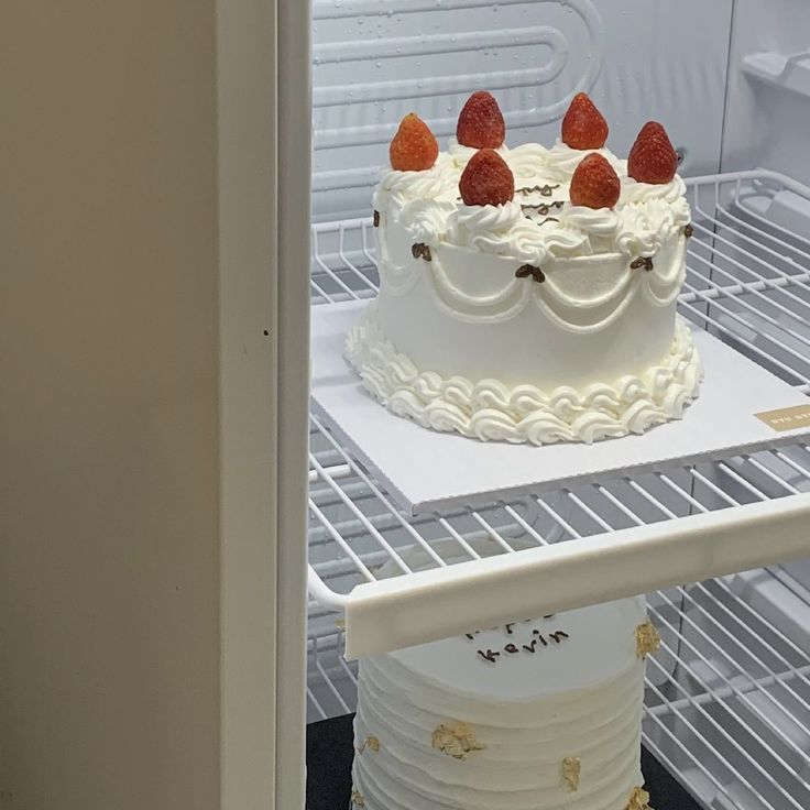 there is a cake with strawberries on it in the refrigerator