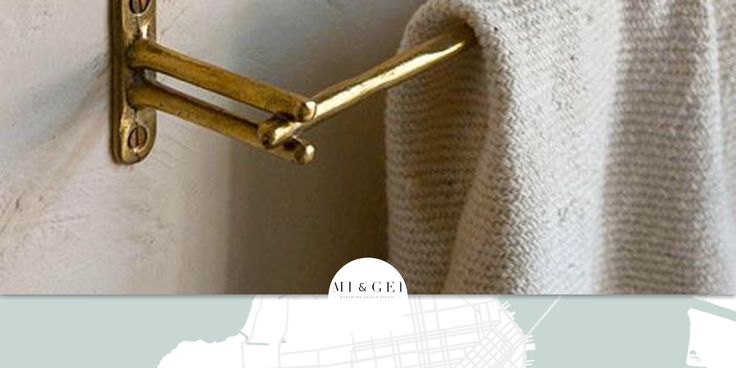 a towel hanging on the side of a white wall next to a curtain with gold hardware