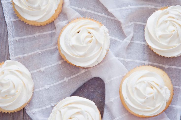 cupcakes with white frosting sitting on top of a table