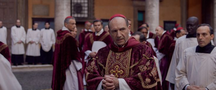 a group of men in red and white robes walking down the street with other people