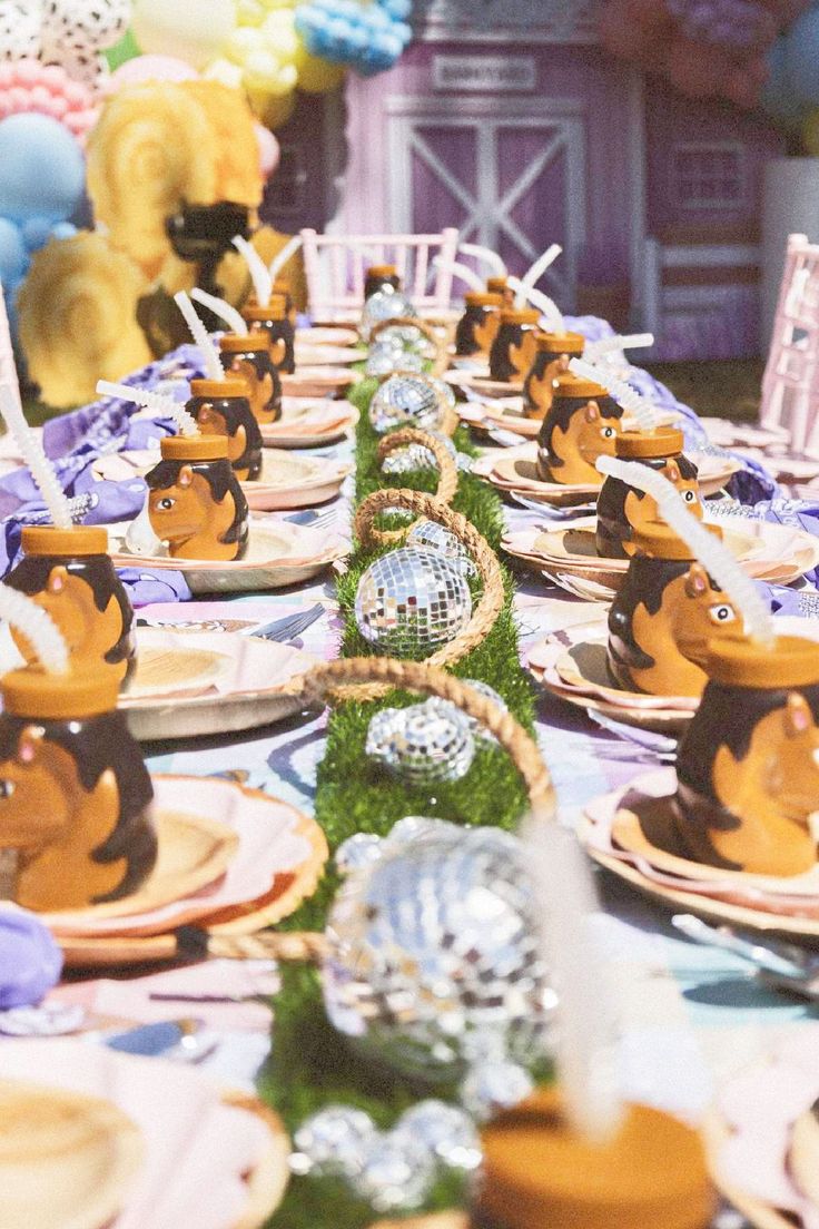 a table set up with plates, bowls and balloons in the shape of cartoon characters